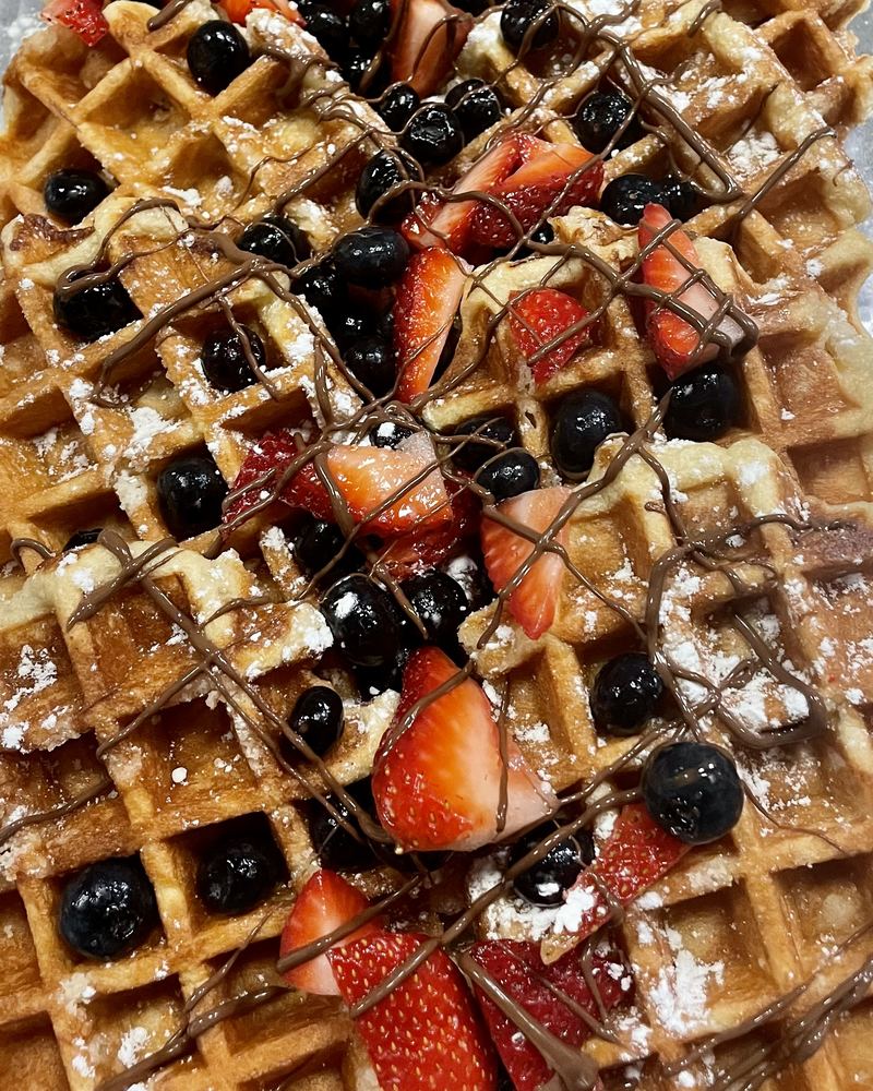 Waffles topped with strawberries, blueberries and chocolate drizzle